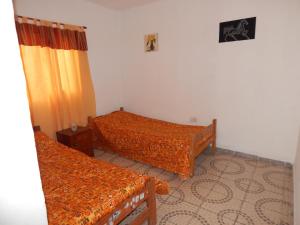 Cette chambre comprend 2 lits avec des couettes en orange. dans l'établissement Rincón de sol, à Cortaderas