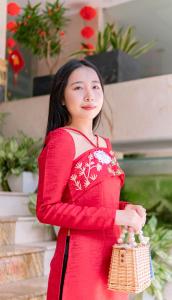 a young woman in a red dress holding a purse at Quoc Cuong Center Da Nang Hotel by Haviland in Danang