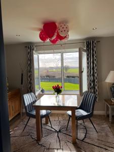 uma sala de jantar com uma mesa e duas cadeiras e balões em Poppy Annex em Wellow