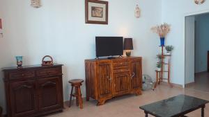 a living room with a tv on a wooden cabinet at A Casa dos Avós in Pêra