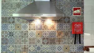 a kitchen with a hood and a tile wall at A Casa dos Avós in Pêra +22 photos