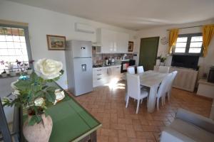 a kitchen and dining room with a table and a white refrigerator at Il Pungitopo in Manciano
