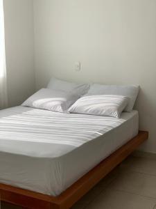 ein Bett mit weißer Bettwäsche und Kissen darauf in der Unterkunft Rosa de Cafeto in Montenegro