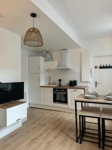 cocina con armarios blancos, mesa y comedor en Appartement T2 hyper centre, en Dieppe
