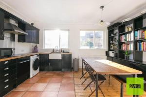 a kitchen with black cabinets and a wooden table at Modern 2 Bedroom with Free Parking & near Tube in London
