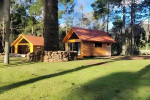 eine kleine Hütte auf einem Feld mit einem Baum in der Unterkunft Cabana Pequeno Bosque com deck e vista p/ o rio in São Joaquim