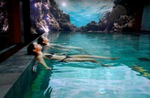twee mensen liggend in het water in een zwembad bij Hotel MiM Sitges & Spa in Sitges