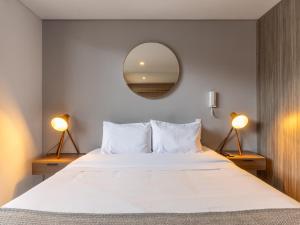 a bedroom with a large white bed with a mirror at The Equilibrium Collection in Centro Internacional in Bogotá