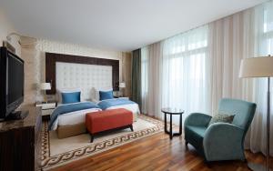 um quarto com uma cama, uma televisão e uma cadeira em Badamdar Hotel and Residences em Baku