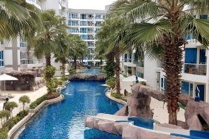 an image of a resort swimming pool with palm trees at Grand Avenue, Luxury Suite, 72sqm pool view with lounge area in Pattaya