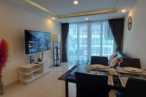a living room with a dining table and a television at Grand Avenue, Luxury Suite, 72sqm pool view with lounge area in Pattaya