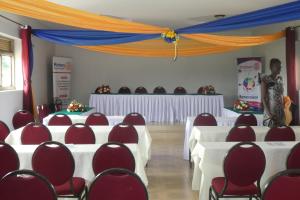 a banquet hall with white tables and red chairs at Acaki Lodge in Kitgum