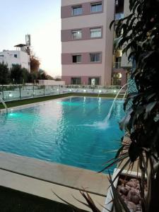 a swimming pool with a fountain in front of a building at Appart S+1 côté club Calypso, Samira Club plage. in Hammamet Sud