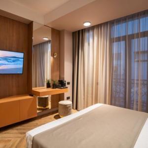 a hotel room with a bed and a television at Boutique ALNIS in Constanţa