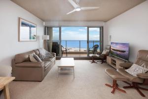 Una sala de estar con un sofá y un televisor de pantalla plana. en Oceanic 7, en Forster