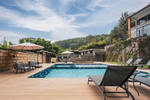 a swimming pool with chairs and an umbrella next to a building at La Fábrica #7 Averly in Valle de Bravo