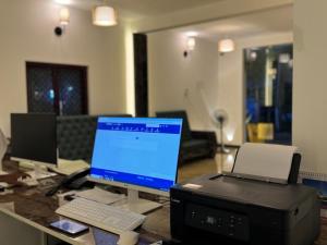 a desk with a computer monitor and a printer at La Antilia Luxury in Puducherry