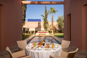 een tafel met eten op een patio met een zwembad bij Al Maaden Villa Hotel & Spa in Marrakesh