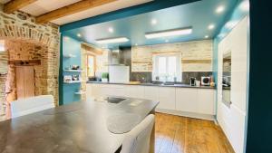 a kitchen with a table and a blue wall at Le Moulin du Gué en Vendée Gite de 8 chambres atypique et exceptionnel au bord de l'eau à 30 minutes du PuyduFou agrémenté d'un Sauna et Bain Nordique au feu de bois pour vous détendre entre Amis et Famille in Sainte-Cécile