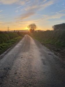 a dirt road with the sun setting in the distance at Knockanree Cottage-Quiet, tranquil country hideaway in Avoca