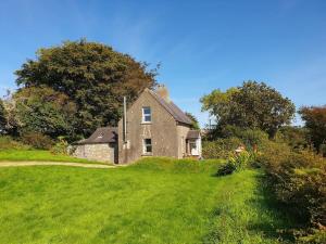 ein altes Haus auf einem Hügel mit einem grünen Hof in der Unterkunft Knockanree Cottage-Quiet, tranquil country hideaway in Avoca