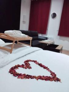 um colar de coração numa cama numa sala de estar em NG SuiteHome - Lille l Tourcoing Winoc - Balnéo - Sauna - Netflix - Wifi em Tourcoing