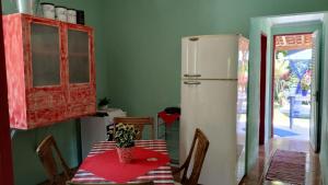 a kitchen with a table and a white refrigerator at Lar do tio Roco em paraty in Paraty