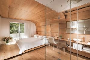 - une chambre avec un lit et un mur en verre dans l'établissement House of Architects, à Vals