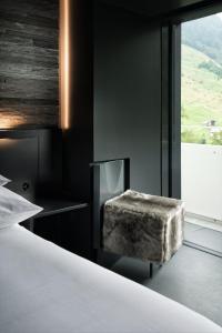 a bedroom with a bed and a chair next to a window at House of Architects in Vals