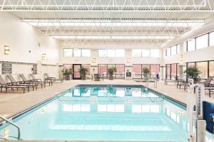 Una piscina en una habitación grande con sillas y mesas. en Delta Hotels by Marriott Minneapolis Northeast, en Minneapolis