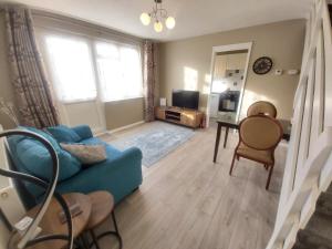 a living room with a blue couch and a table at Corner Cottage in Totland