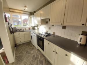 a kitchen with white cabinets and a stove top oven at Corner Cottage in Totland