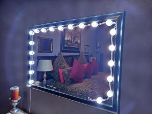 a mirror with a bed with red pillows and lights at Suikerbosrant Sleep and go in Pretoria