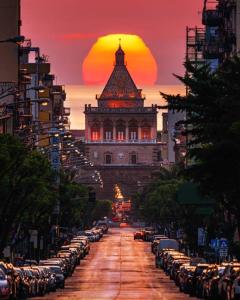 a city street with a building with a sunset in the background at la porta di Alba in Palermo