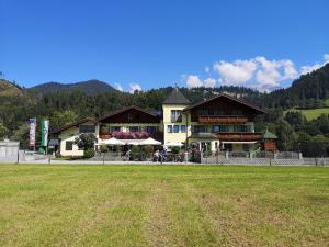 a large building with a grass field in front of it at Hotel Cafe' Hermann in Schladming