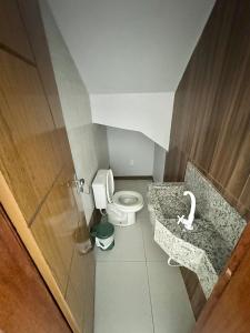 a small bathroom with a toilet and a sink at La casa de 3 suítes em Guriri - equipada para 8 pessoas in São Mateus