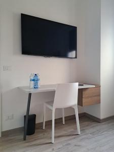 mesa blanca con silla y TV en la pared en Il Campanone - Sassuolo Centro - parcheggio auto coperto - self check-in, en Sassuolo