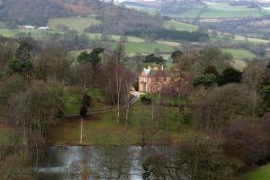 a large house on a hill next to a body of water at The Coach House at Bryngwyn Hall in Llanfyllin