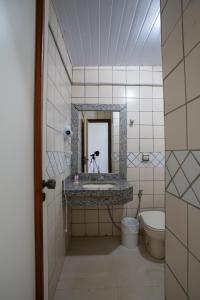 a bathroom with a sink and a mirror and a toilet at Hotel Apollo in Uberlândia