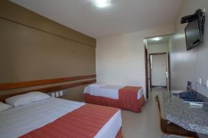 a hotel room with two beds and a mirror at Hotel Apollo in Uberlândia