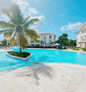 une grande piscine avec un palmier en face d'un bâtiment dans l'établissement Apartamento Cadaques caribe Bayahibe, à Bayahibe