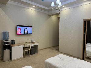 a bedroom with a desk and a tv on the wall at Resident Hotel in Tashkent