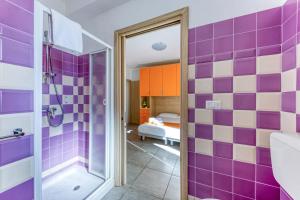 ein Badezimmer mit lila und weiß gefliesten Wänden in der Unterkunft Camere con vista mare a 30 m dal mare in Torre San Giovanni Ugento