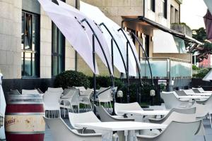 a row of white tables and chairs with umbrellas at Hotel Alda Carril in Vilagarcia de Arousa