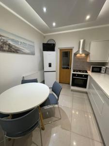 a white kitchen with a white table and chairs at Modern, spacious and Central Location in Aberdare