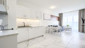 a white kitchen with white cabinets and a table at Apartamenty Sun & Snow AQUAMARINA Onyx in Międzyzdroje