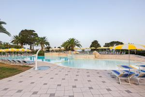 a large swimming pool with chairs and umbrellas at Labranda Rocca Nettuno Tropea in Tropea