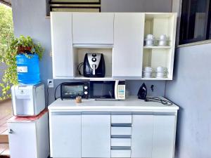 uma cozinha com armários brancos e electrodomésticos num balcão em Studio #1 Conforto em Campos dos Goytacazes