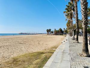 una playa con una fila de palmeras y el océano en Golden Port Cambrils, en Cambrils
