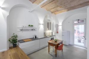a kitchen with white cabinets and a wooden table at FAMM Apartments - Charming open space in Trastevere in Rome